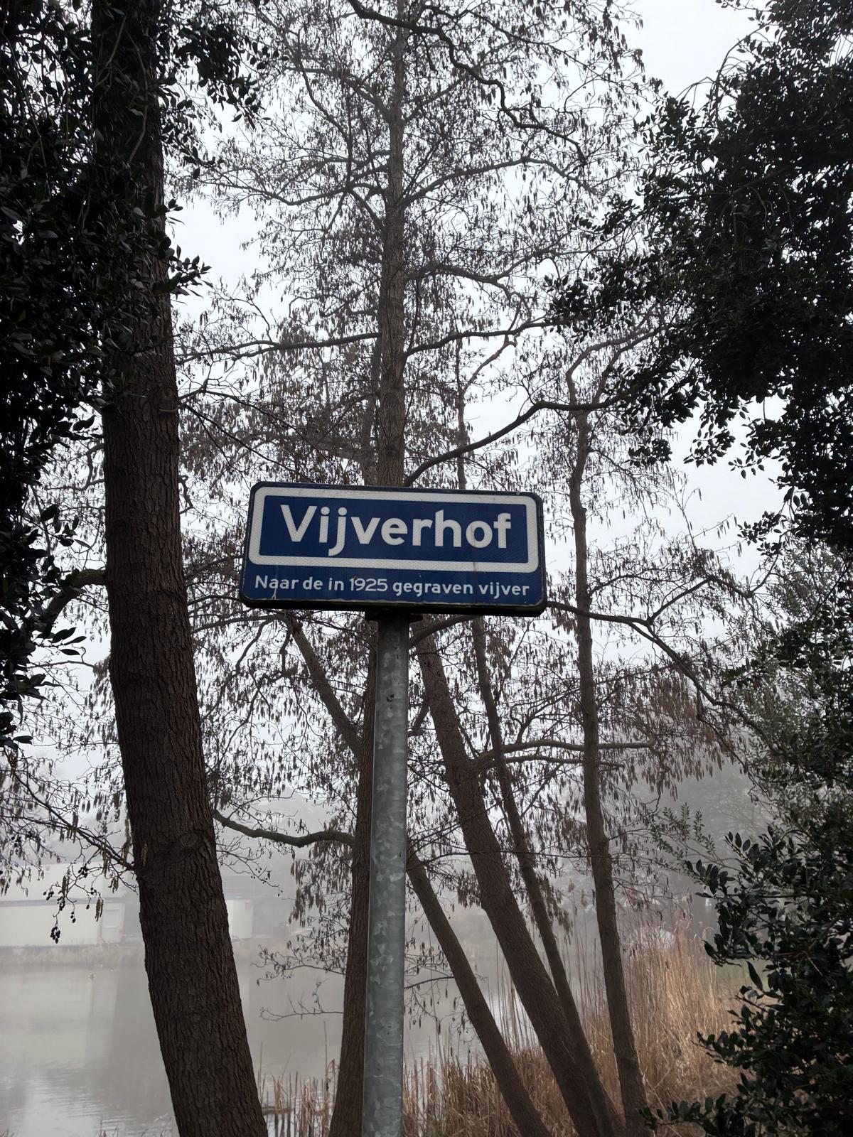 Blauw straatnaambord Vijverhof met de tekst: Naar de in 1925 gegraven vijver
